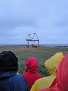 Scene uit de voorstelling ''Er zal iemand komen'' van Ilmer Rozendaal. De Waddenzee bij de Wierschuur in Oosterend vormt een mooi decor achter het verlaten huisje.